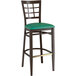 A Lancaster Table & Seating Spartan Series metal bar stool with a green vinyl seat and a black frame.