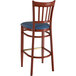 A Lancaster Table & Seating wooden bar stool with mahogany wood grain finish and navy blue vinyl seat.