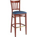 A Lancaster Table & Seating metal slat back bar stool with mahogany wood grain finish and navy vinyl seat.