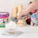 A person using a Vollrath #10 aluminum ice cream scoop to scoop ice cream.