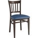 A Lancaster Table & Seating Spartan Series metal slat back chair with dark walnut wood grain finish and navy vinyl seat.