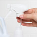 A hand holding a white plastic bottle with a  Noble Chemical 10" Foaming Spray Trigger on top.