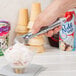 A hand using a Vollrath aluminum ice cream scoop to scoop ice cream.