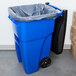 A blue Rubbermaid rectangular trash can with a black handle and lid.
