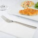 An Arcoroc stainless steel dinner fork on a white plate.
