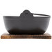 A black cast iron Japanese noodle bowl with a wooden stand and lid.