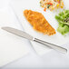 An Arcoroc stainless steel dinner knife on a plate of food