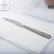 An Arcoroc stainless steel dessert knife on a white napkin.