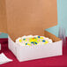 A white 14" x 14" x 6" bakery box with a cake inside.