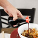 A hand holding a Town Red Top Soy Sauce bottle pouring sauce into a bowl of food.