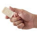 A hand holding a white bar of Dial deodorant soap.