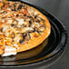 A Solut black paperboard pizza tray with a pizza topped with mushrooms and cheese.