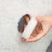 A hand holding a 3M Natural Blend white floor pad.
