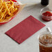 A basket of french fries and a red napkin on a white surface.