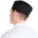 A man wearing a black Chef Revival baker's skull cap with a mesh top.