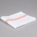 A folded white napkin with orange stripes.