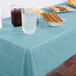 A table with a Pastel Blue Creative Converting plastic tablecloth and food on it.
