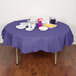 A table with a purple Creative Converting OctyRound tablecloth, plates, and utensils.