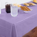 A Luscious Lavender purple plastic table cover on a table with cookies, drinks, and food.