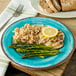 A Carlisle Aqua Melamine Plate with rice, asparagus, and chicken with a lemon wedge on top.