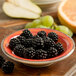 A Carlisle Mingle melamine fruit bowl filled with blackberries on a table.