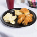 A Creative Converting black velvet paper plate with fried chicken, mashed potatoes, and coleslaw on a table.