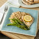 A Carlisle Aqua Square Melamine Plate with rice, chicken, and asparagus with a lemon slice on top.