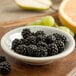 A Carlisle smoke melamine fruit bowl filled with blackberries on a table.