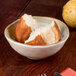 A Carlisle adobe melamine dip bowl filled with bread with a pear on top.