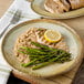 A Carlisle round melamine plate with asparagus, rice, and chicken with a lemon slice on top.