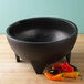 A black Grandote molcajete filled with peppers on a counter.