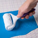 A hand using a white Wilton quilt pattern roller to smooth fondant.