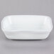 A white rectangular Tuxton side dish with a curved edge.