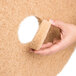 A hand holding a 3M tan circular burnishing pad with a white center.