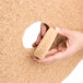 A hand holding a 3M tan burnishing floor pad.