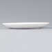 A white Arcoroc Candour porcelain plate with a rim on a grey surface.