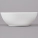 An Arcoroc white porcelain bowl on a gray background.