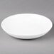 An Arcoroc white porcelain plate with a deep coupe shape on a gray surface.