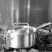 A Vollrath stainless steel pot cover with a loop handle on a stainless steel pot.