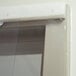A close up of a white plastic strip door on a window.