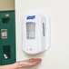 A person using a Purell hand sanitizer dispenser.