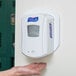 A hand reaching out to a Purell LTX hand sanitizer dispenser on a wall.