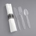 A white pre-rolled napkin with clear plastic cutlery, including a spoon with a white handle.