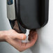 A hand using a GOJO Clear & Mild foaming hand soap dispenser.