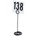 An American Metalcraft black swirl base card holder with a white table number sign on it.