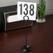 An American Metalcraft black swirl base card holder with a white table number sign with black numbers.