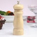 A Chef Specialties Salem natural finish wooden pepper mill on a white table.