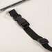 A black strap with a metal clasp on a white surface.