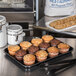 A Carlisle black fiberglass market tray of muffins on a counter.