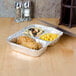 A foil tray with three compartments of food on a table.